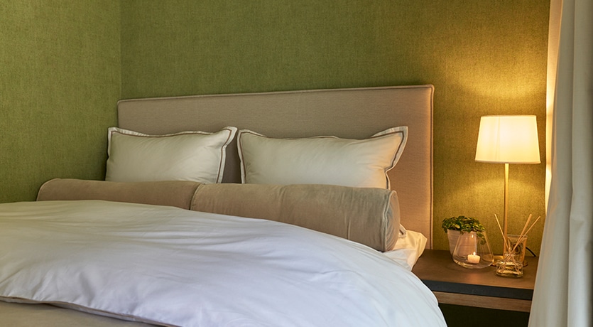 Eventyrlig oppussing. Interiør soverom med grønne vegger, beige seng med lyst sengetøy.
